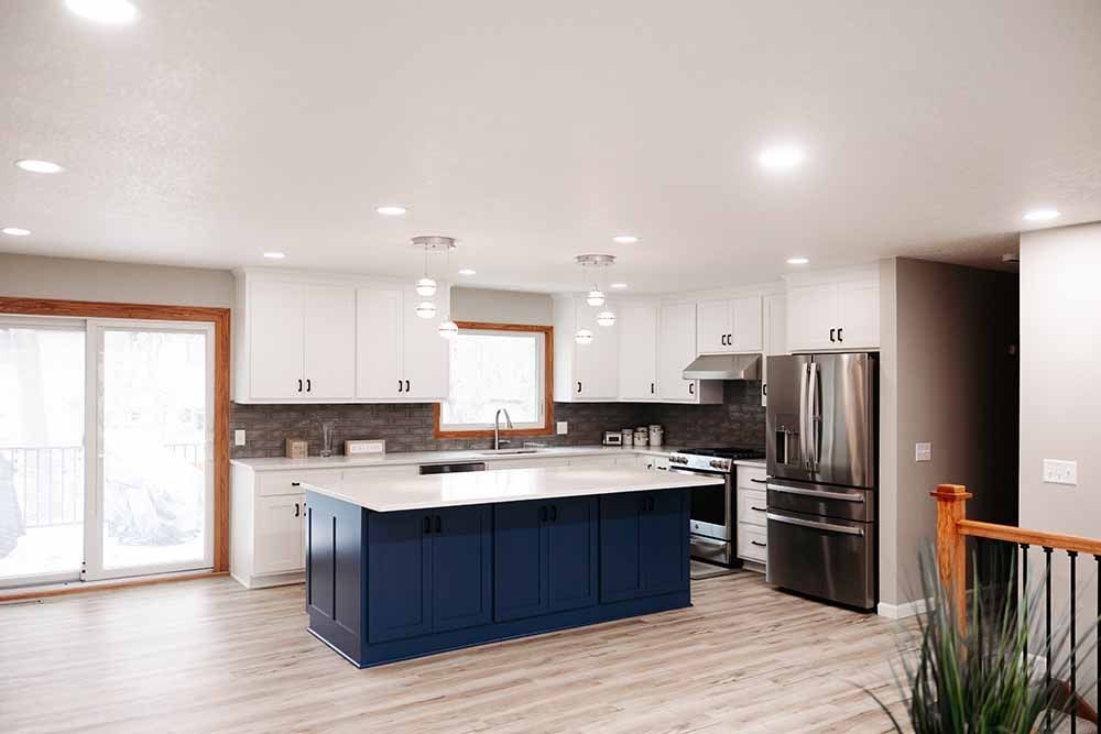 A kitchen with blue cabinets , white cabinets , stainless steel appliances and a large island.