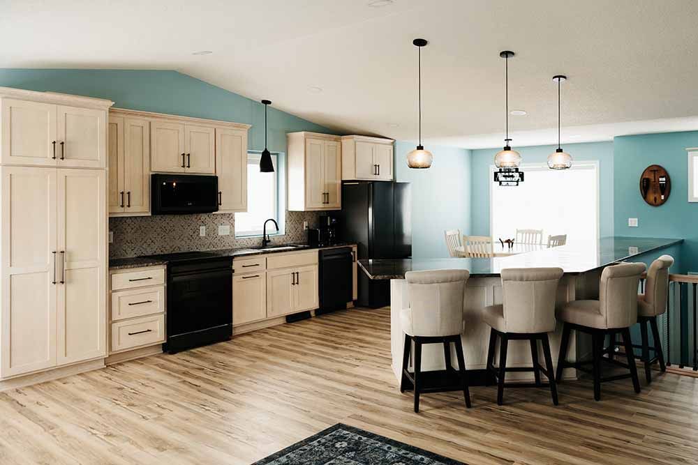 A kitchen with white cabinets , black appliances , and a large island.