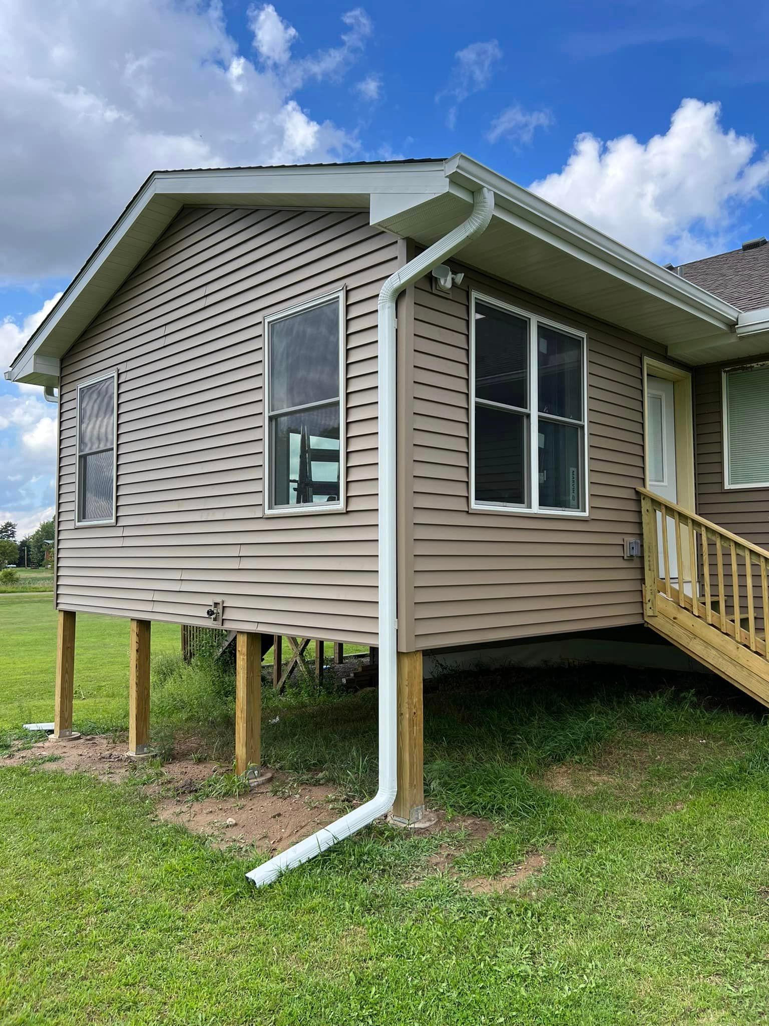 A house on stilts with a white gutter on the side of it.
