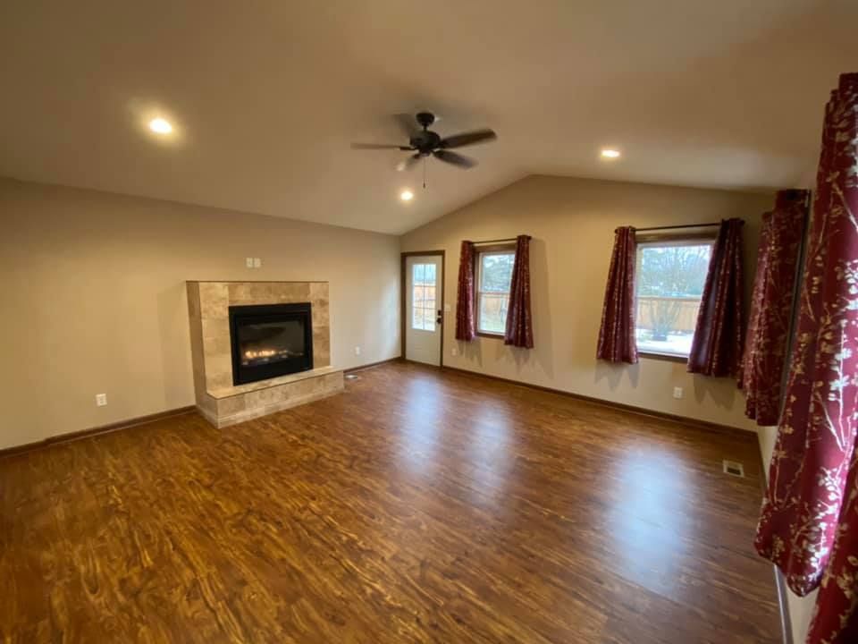 A living room with hardwood floors, a fireplace and a ceiling fan.