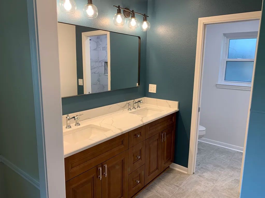 A bathroom with two sinks , a mirror and a toilet.