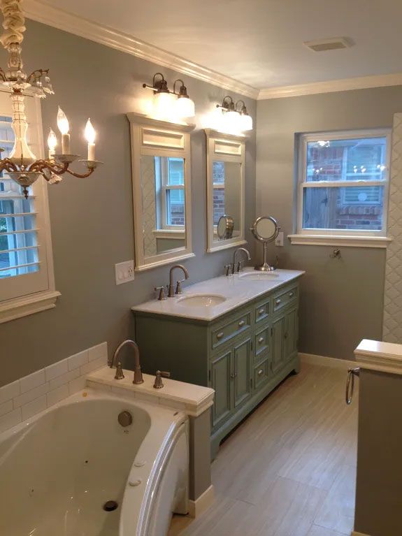 A bathroom with two sinks , two mirrors , a tub and a window.