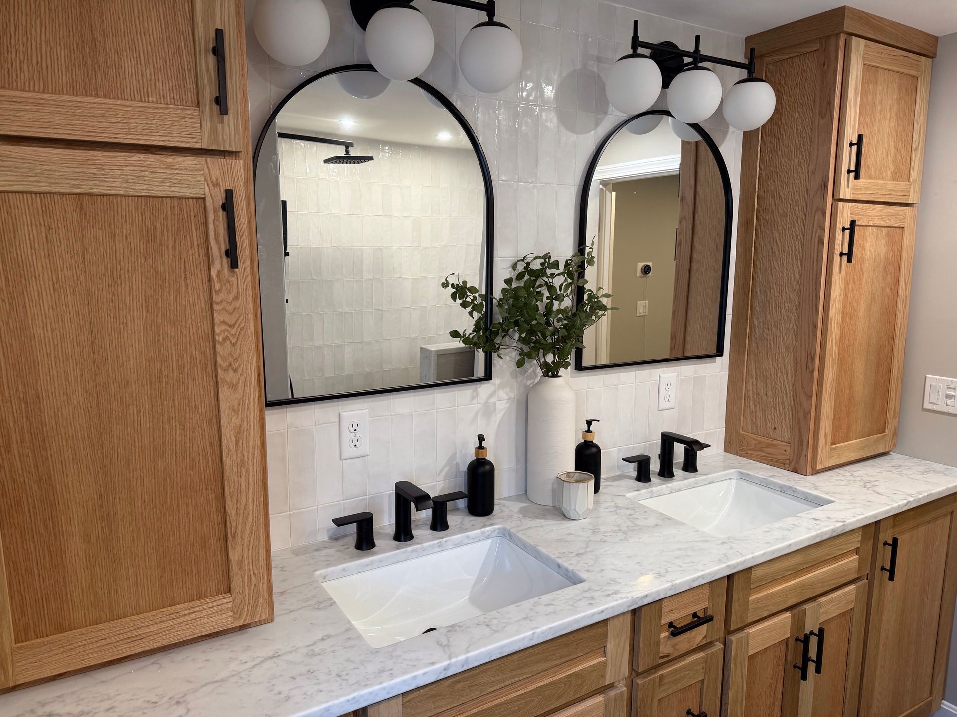 A bathroom with two sinks , two mirrors , and wooden cabinets.