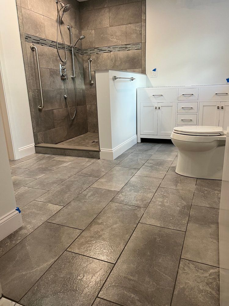 A bathroom with a toilet , sink , shower and tiled floor.