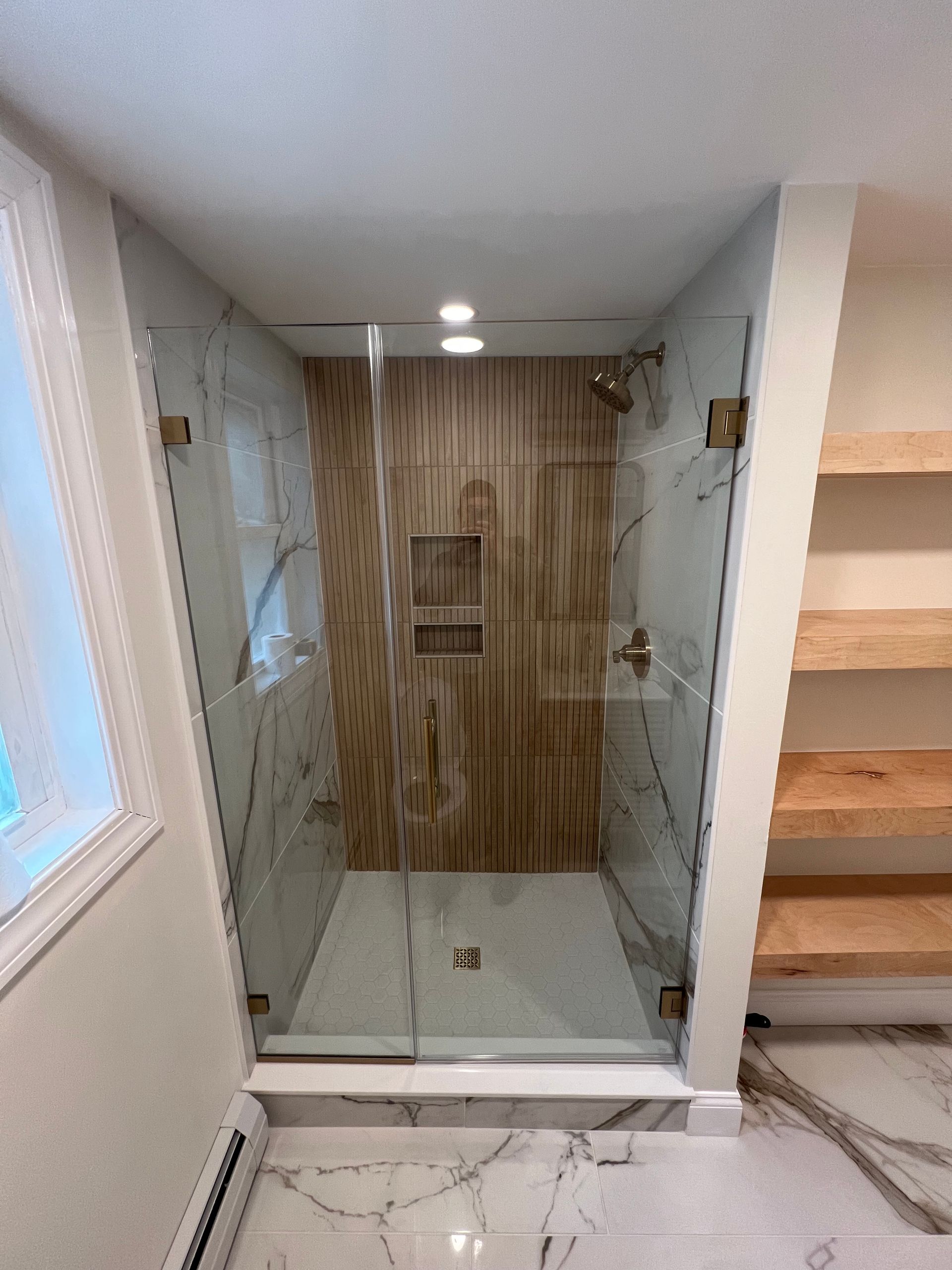 A bathroom with a walk in shower with a glass door.
