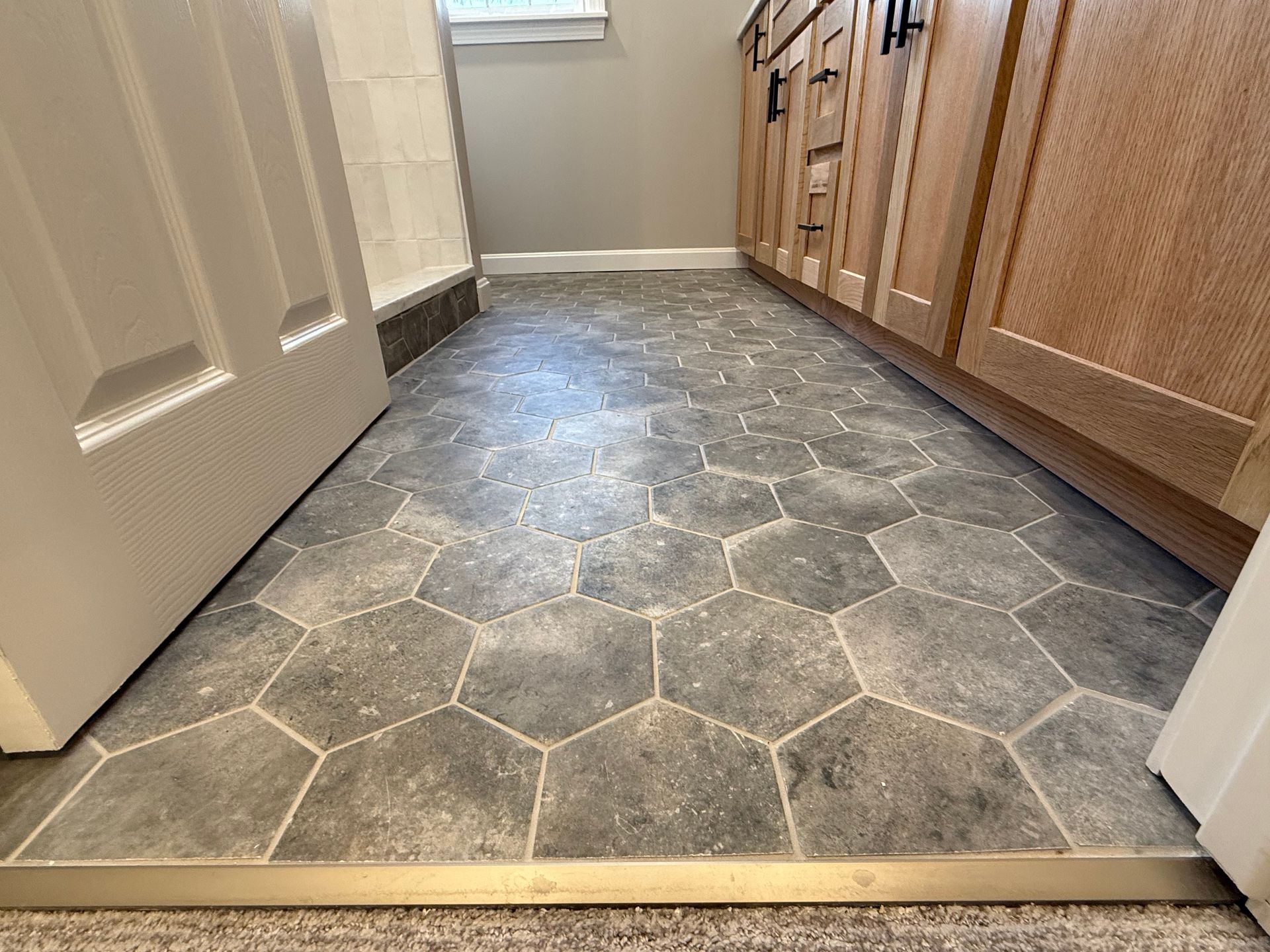 A bathroom with a tile floor and wooden cabinets.