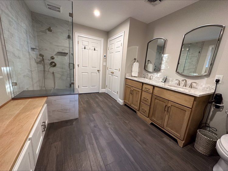 A bathroom with two sinks , a toilet , and a walk in shower.