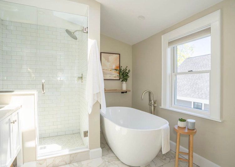 A bathroom with a tub , shower and window.