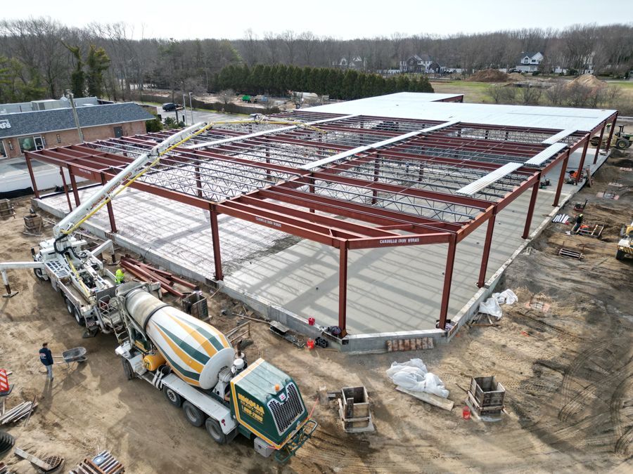 Aerial view of a steel building frame under construction with a concrete truck below
