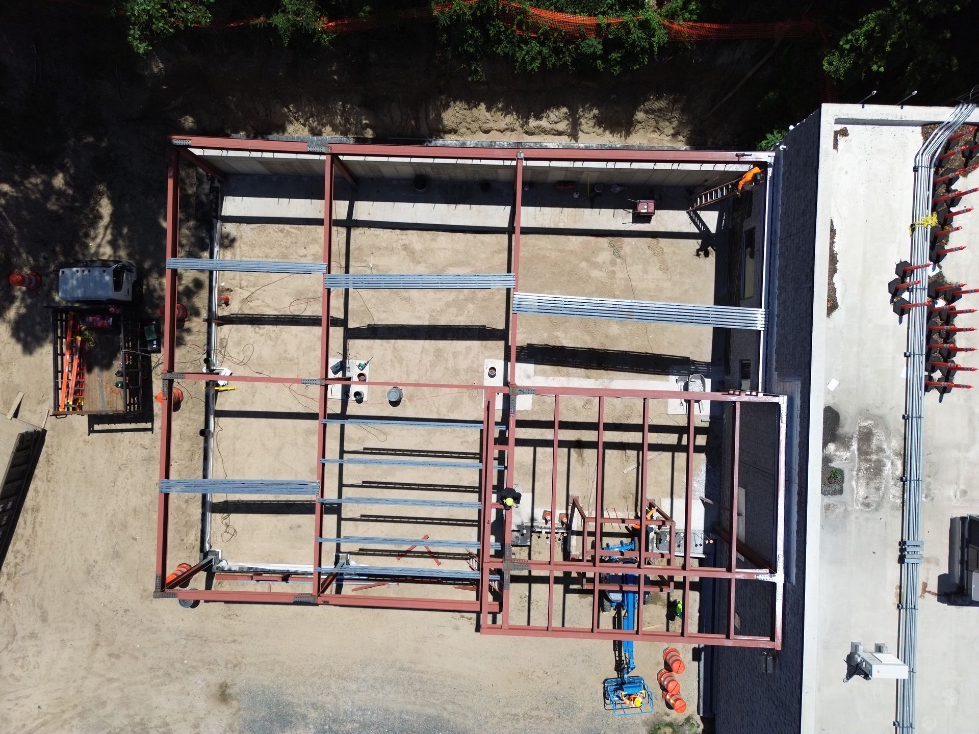 Construction site with a steel building frame and ladders viewed from above