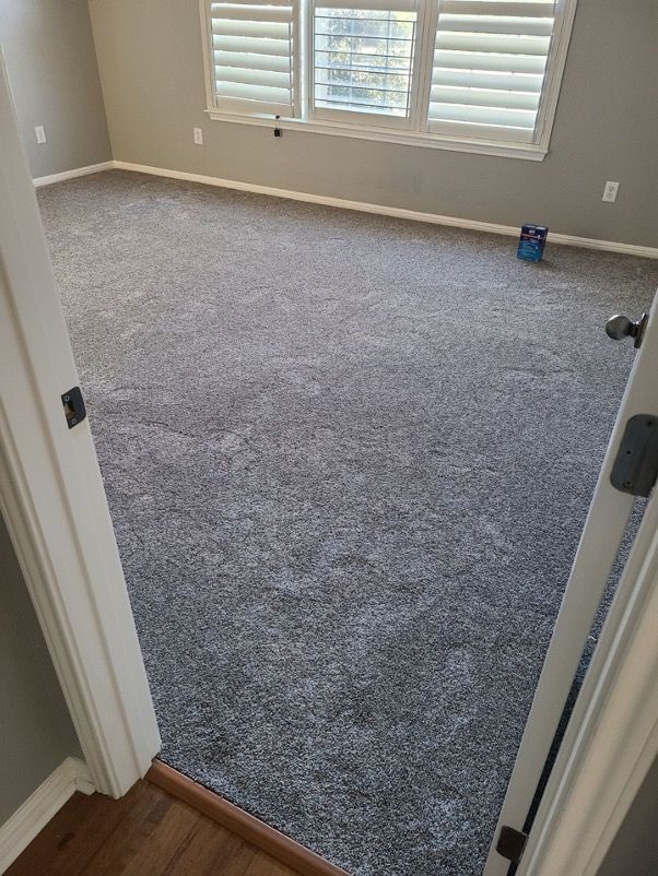 A bedroom with a large carpeted floor and shutters on the windows.