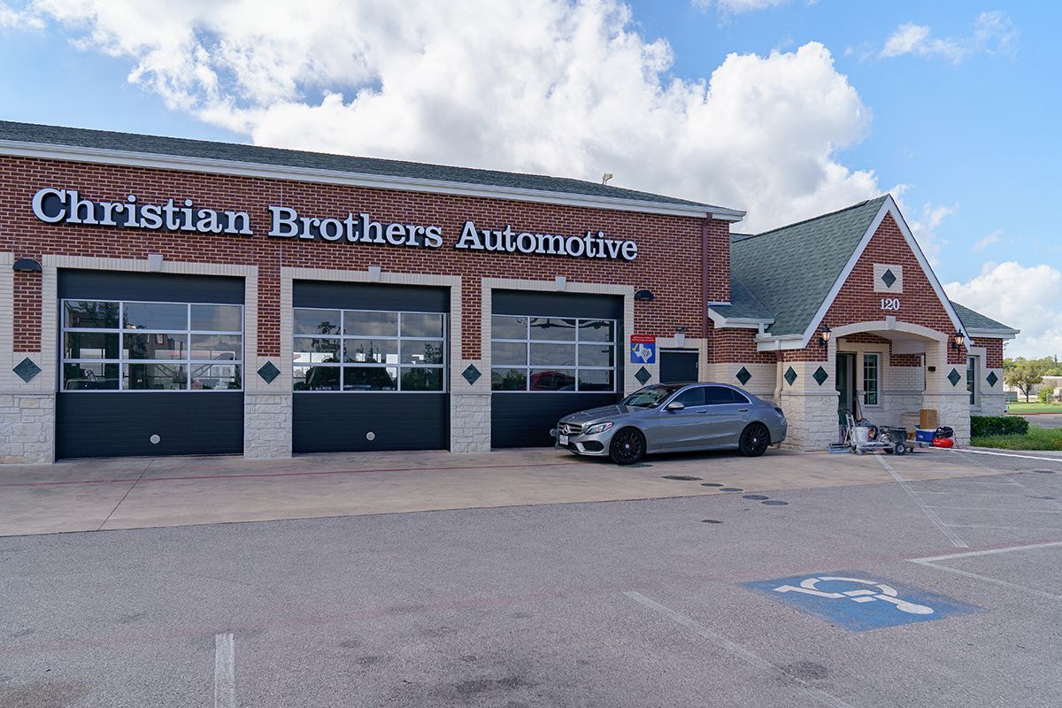 A car is parked in front of a christian brothers automotive garage.