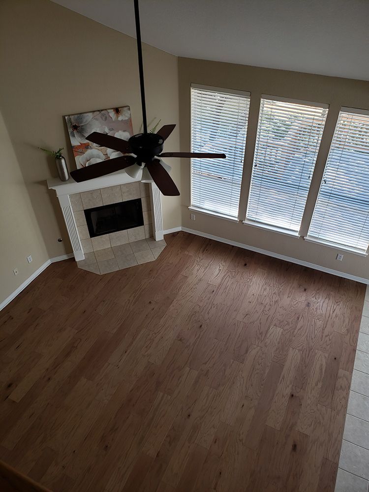 A living room with hardwood floors , a fireplace and a ceiling fan.