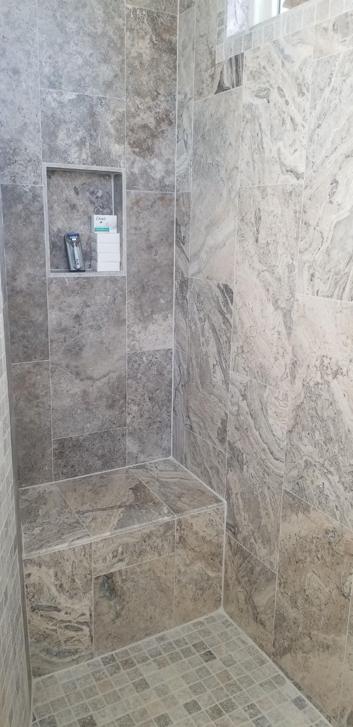 A bathroom with a walk in shower and a shelf.