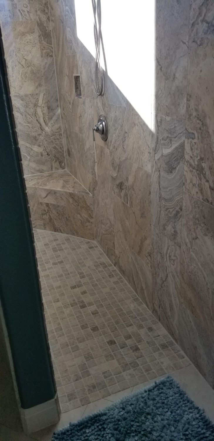 A bathroom with a walk in shower and a blue rug.