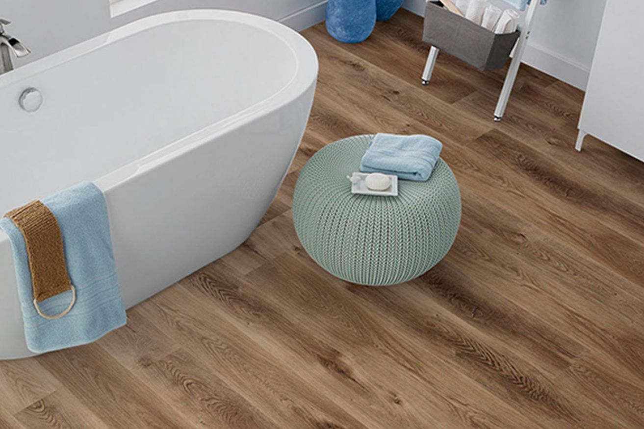 A bathroom with a bathtub and a wooden floor.