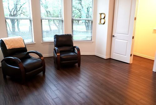 A living room with two chairs and a letter b on the wall.