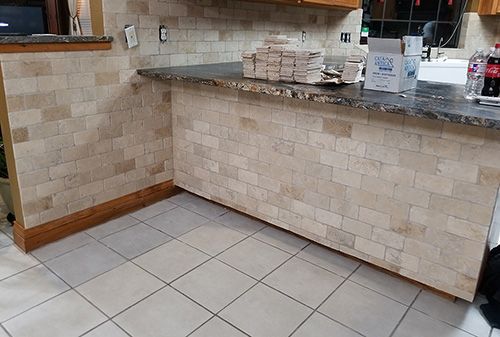 A kitchen with a brick wall and a tiled floor.