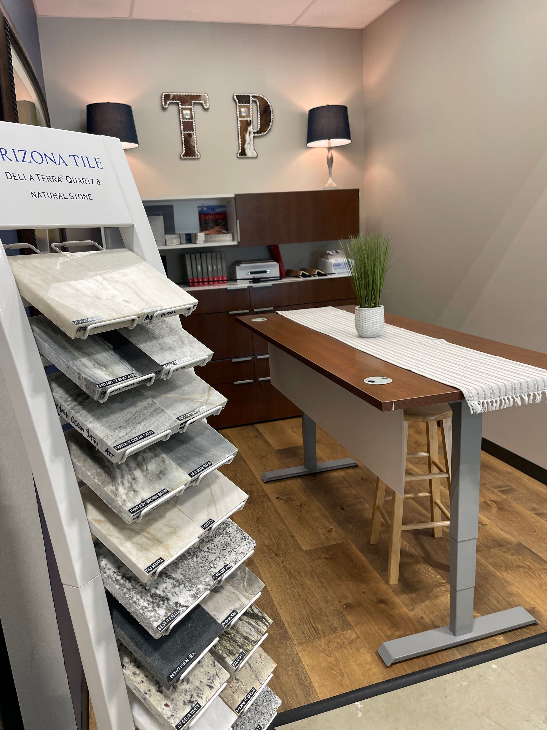 A room with a table and stools and a display of granite tiles.