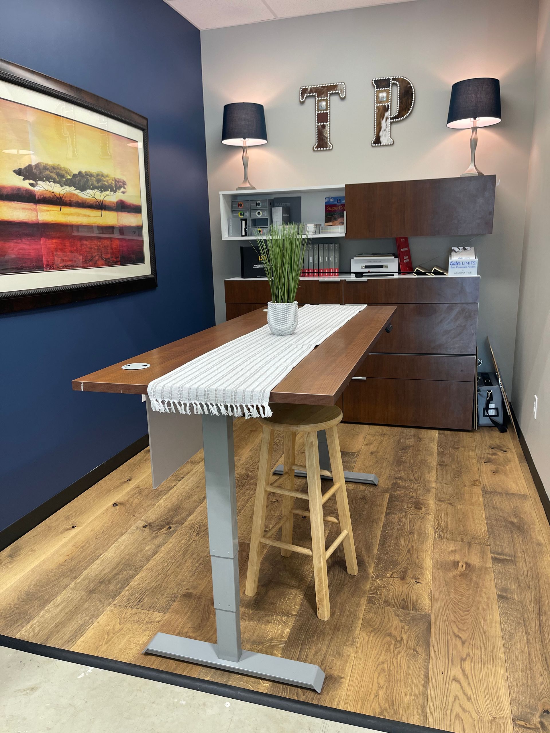 A room with a table and stools and a picture on the wall.