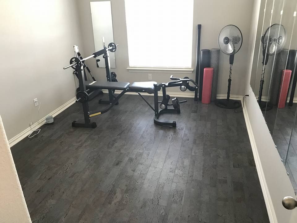A home gym with a bench , barbell , and mirror.
