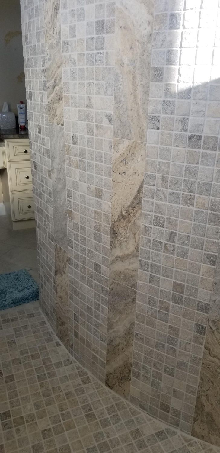 A bathroom with a walk in shower and a tiled floor.