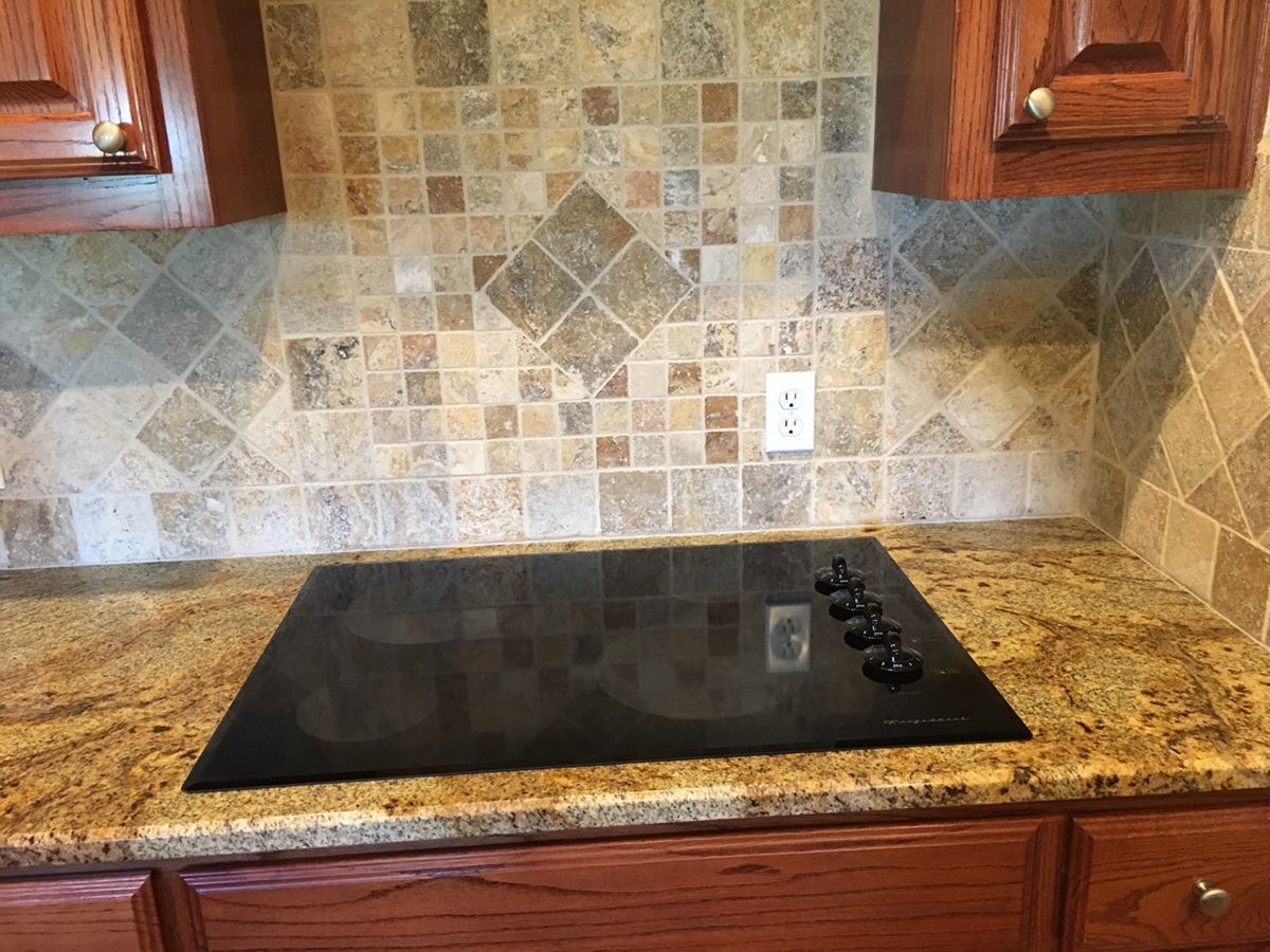 A black stove top oven is sitting on top of a granite counter in a kitchen.