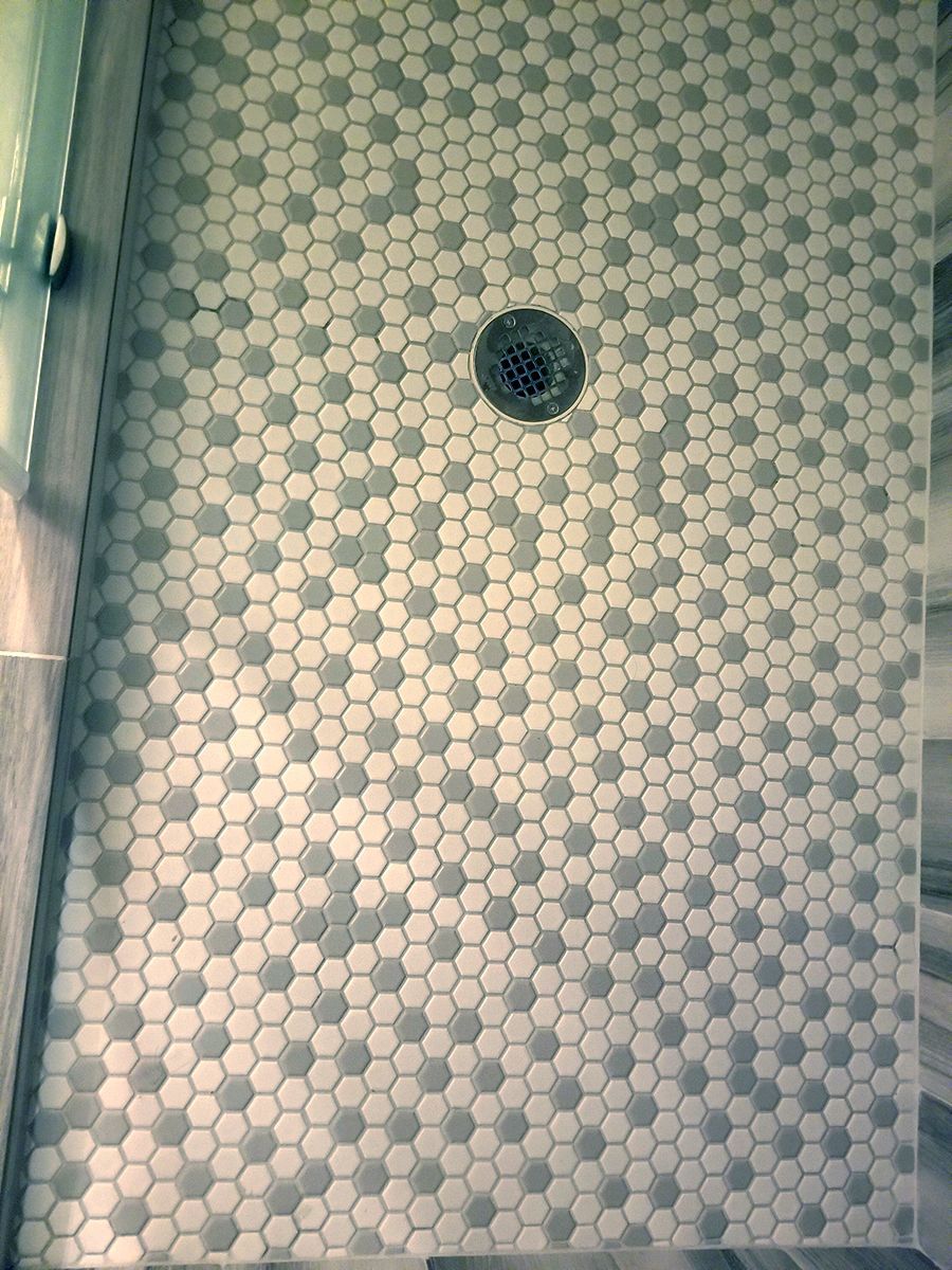 A shower floor with hexagonal tiles and a drain