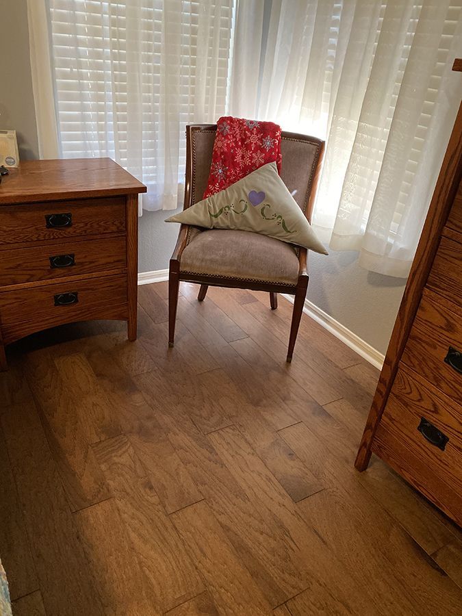 A chair with a pillow on it is sitting in a room next to a window.