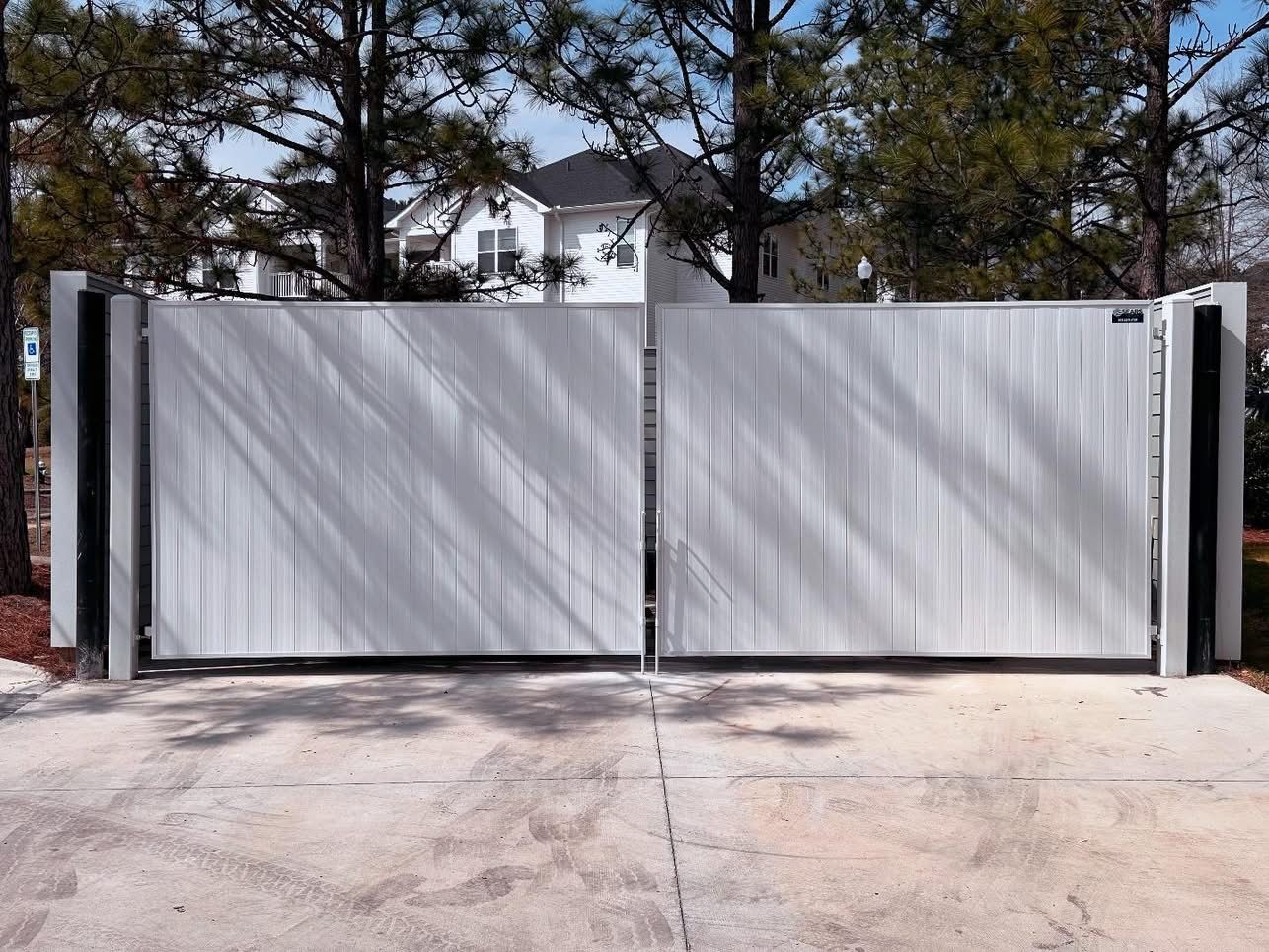 Gray metal driveway gate closed in front of a house.