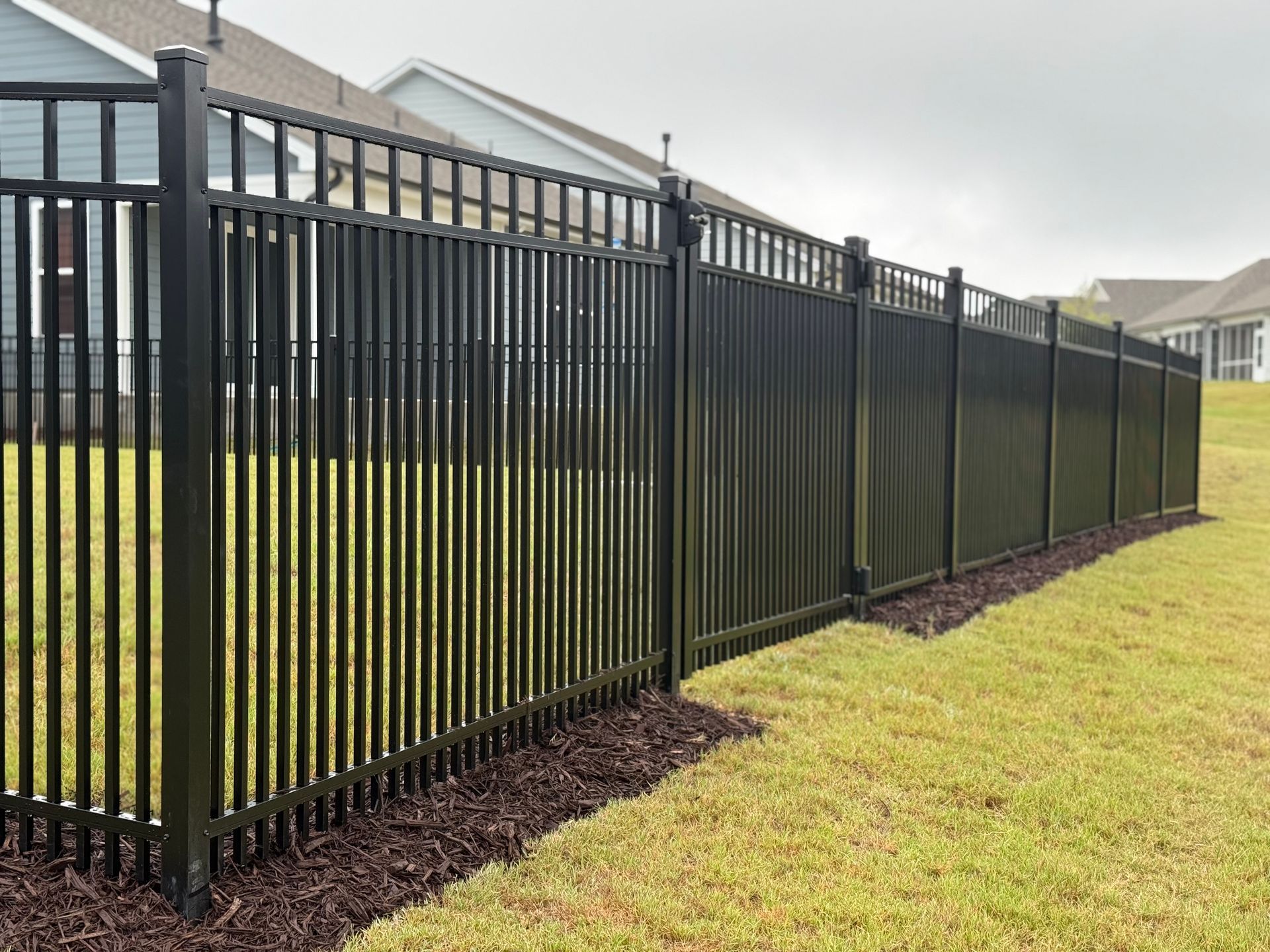Black metal fence enclosing a grassy yard.