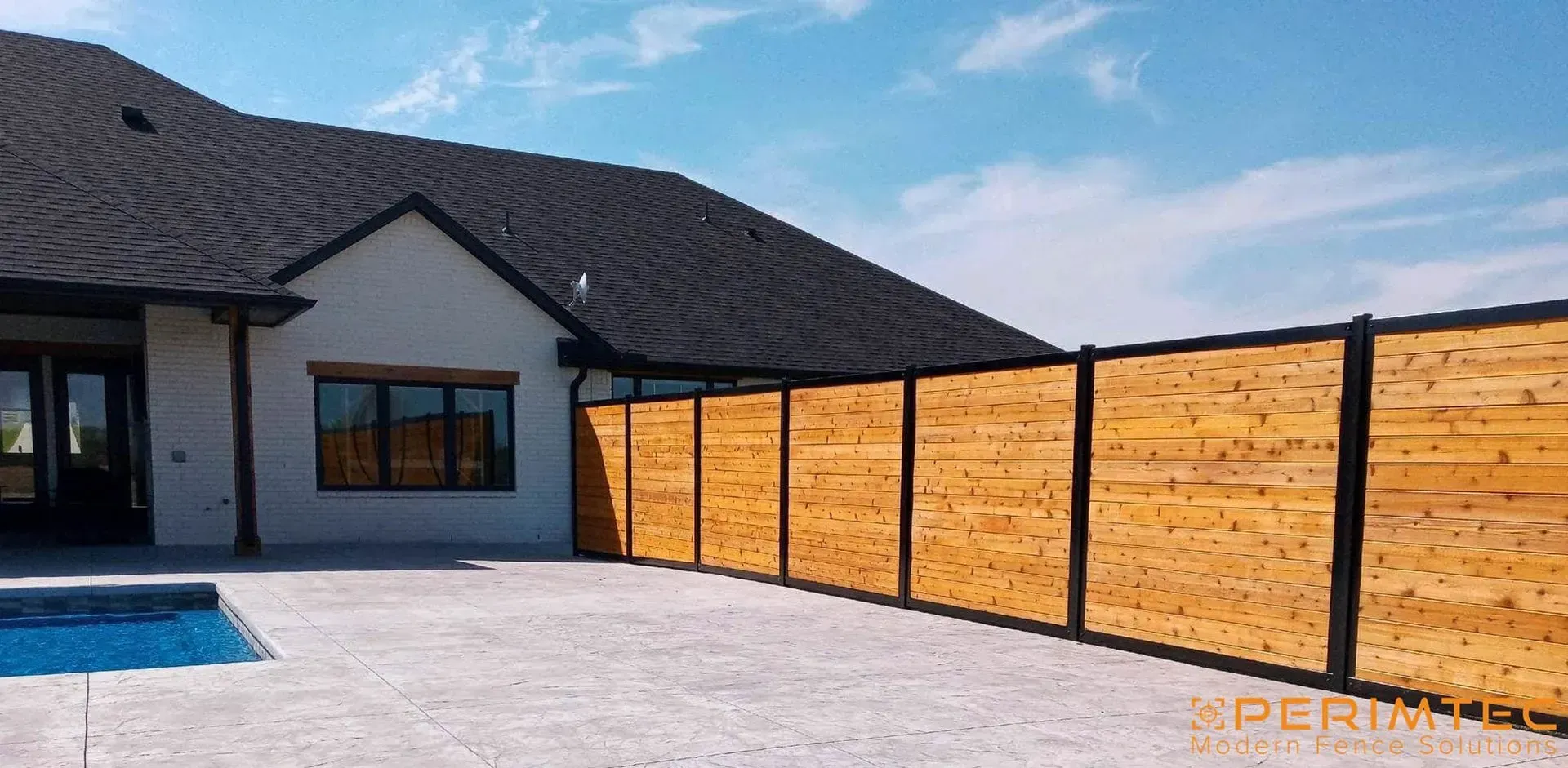 A modern home with a wooden fence and a pool on a sunny day.