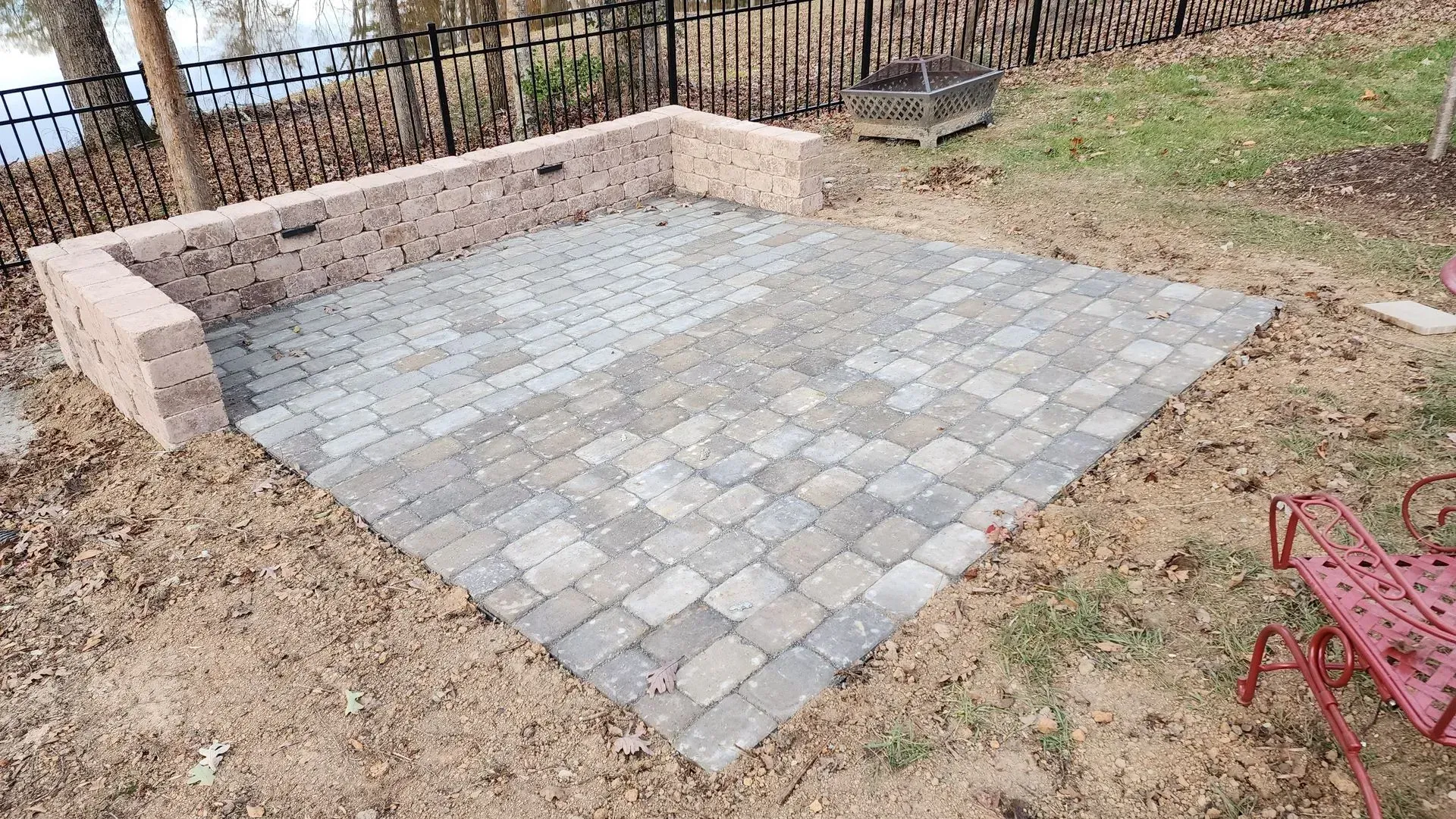 Brick patio area with brick retaining wall, next to a lake.