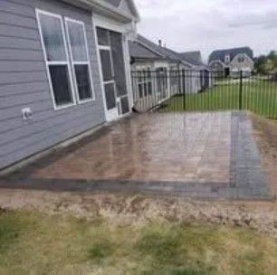 Backyard patio with brick border and house in background.