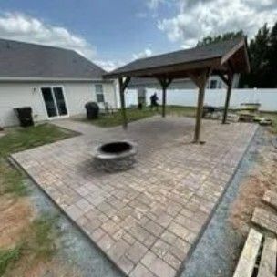 Brick patio with fire pit, wooden pergola, and house in the background.