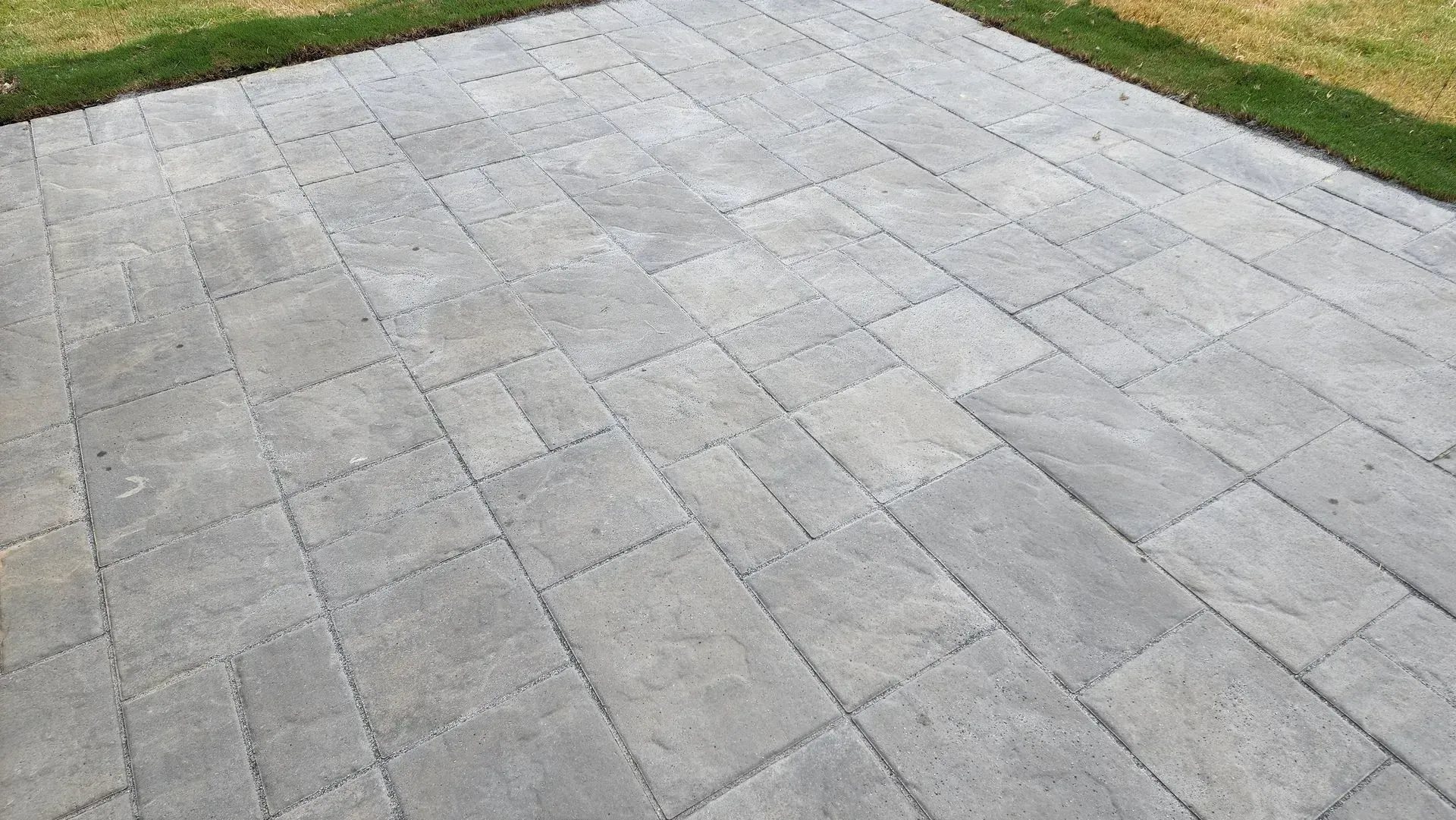 Gray brick patio with grass border.