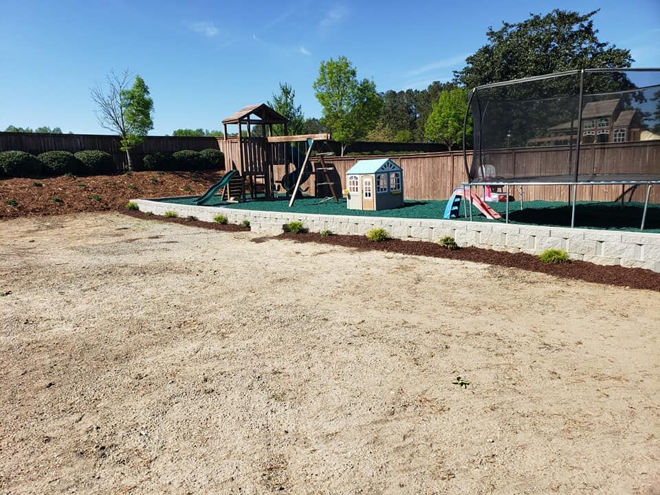 Backyard with playground equipment and trampoline set on green matting.