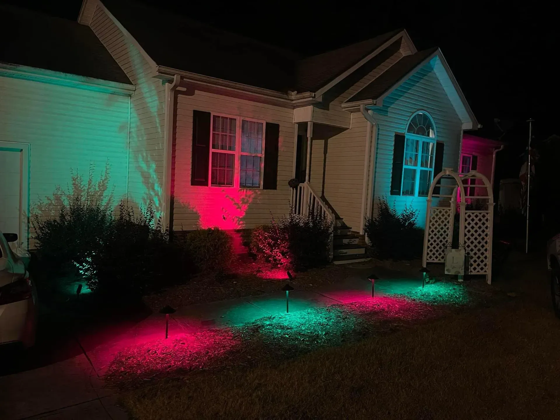 A house exterior illuminated by red and green spotlights in a nighttime setting.