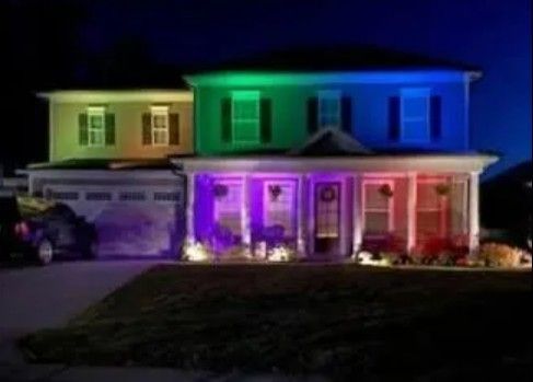 House at night illuminated with colorful lights, including green, blue, pink, and red.