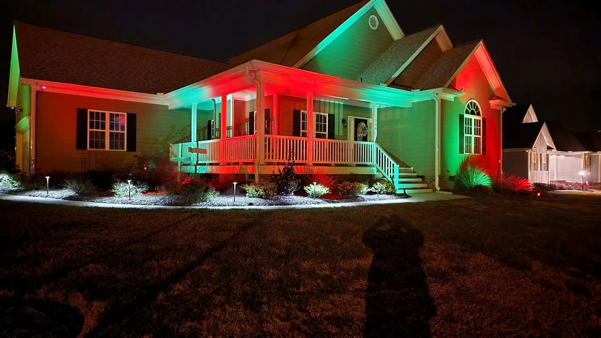 House lit with red and green lights for the holidays at night.