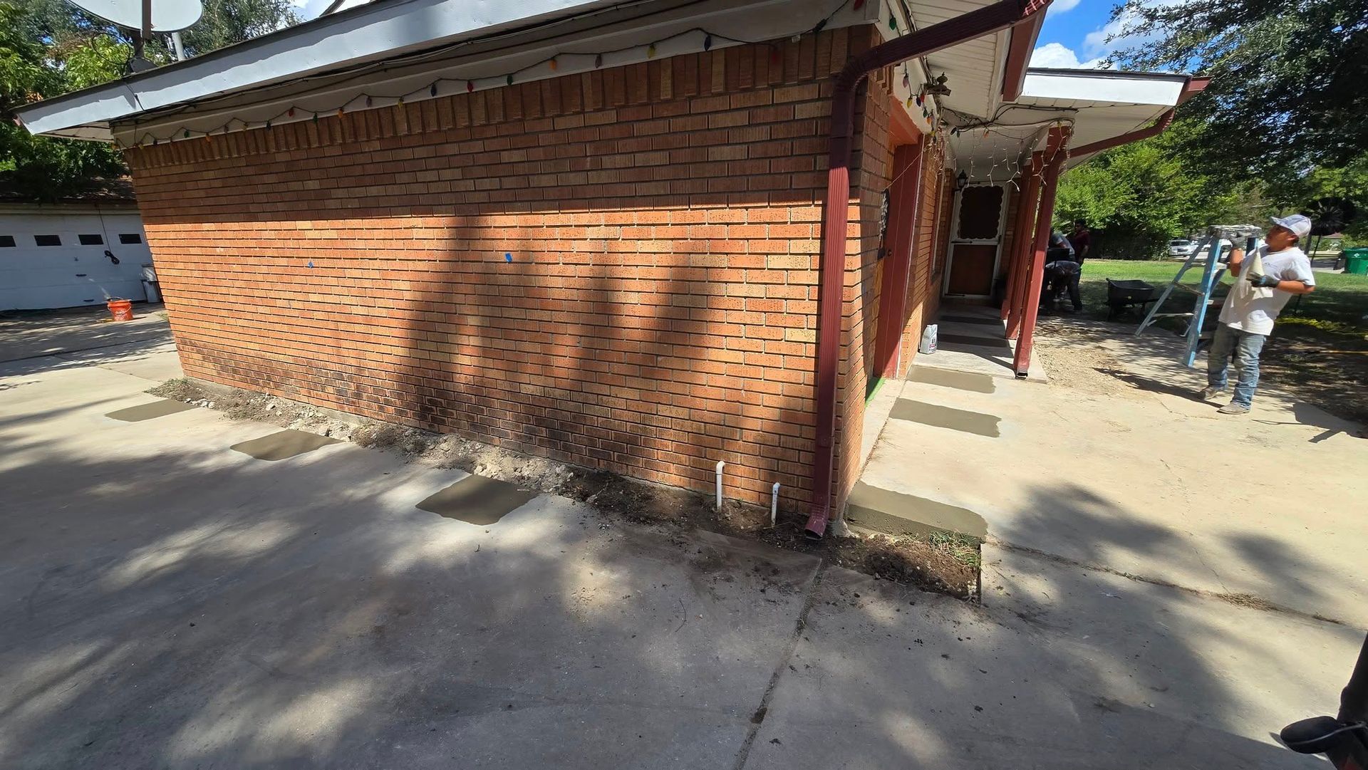 Brick building with curved brickwork, red gutters, and a person working outside.