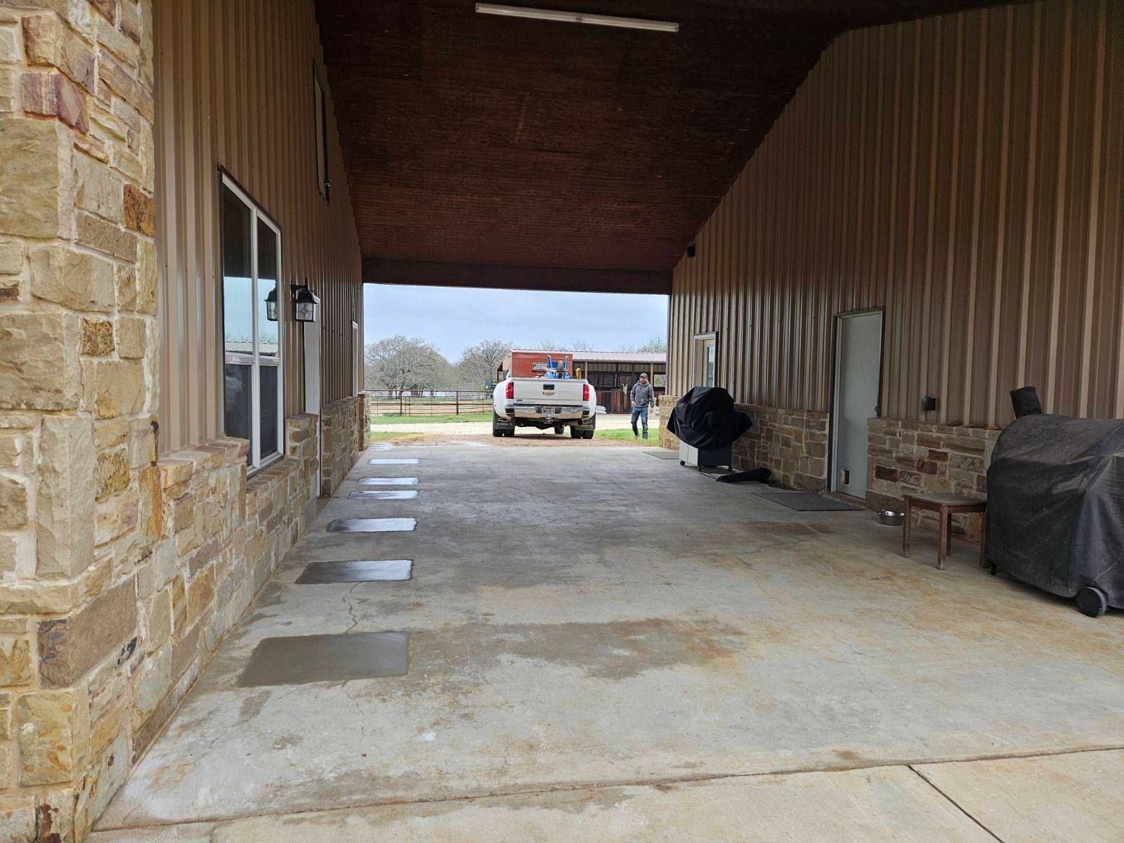 Open covered walkway with a truck at the end; stone and metal exterior, overcast day.