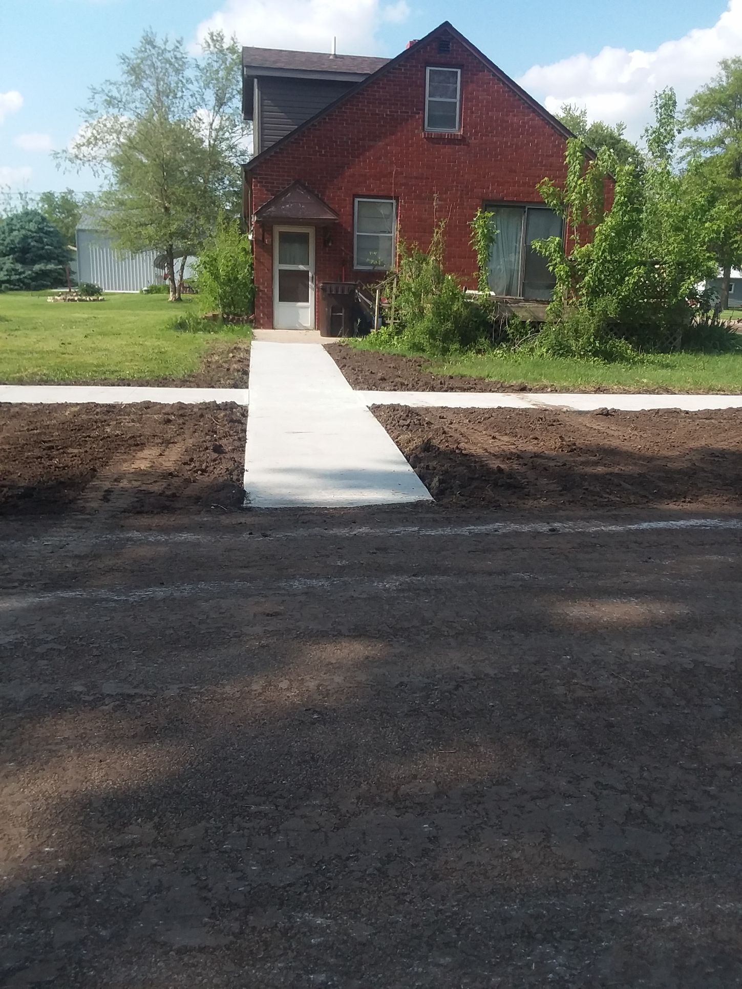 A brick house with a concrete walkway leading to it