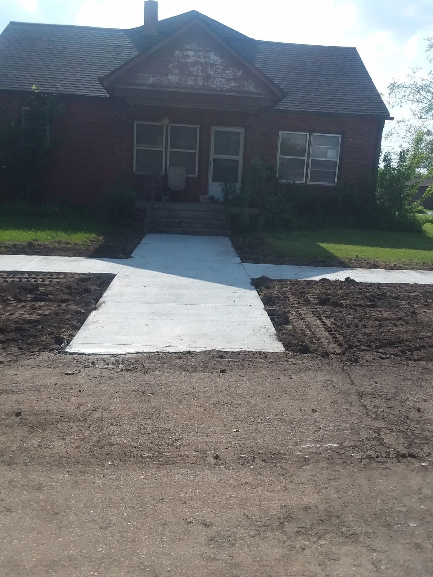A brick house with a concrete walkway leading to it