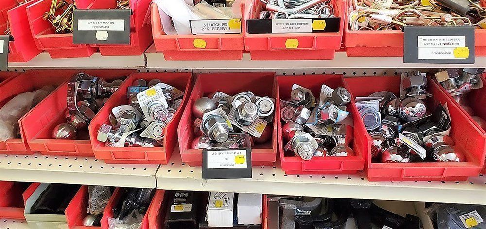 Red bins of assorted metal fasteners and hardware parts on warehouse shelves