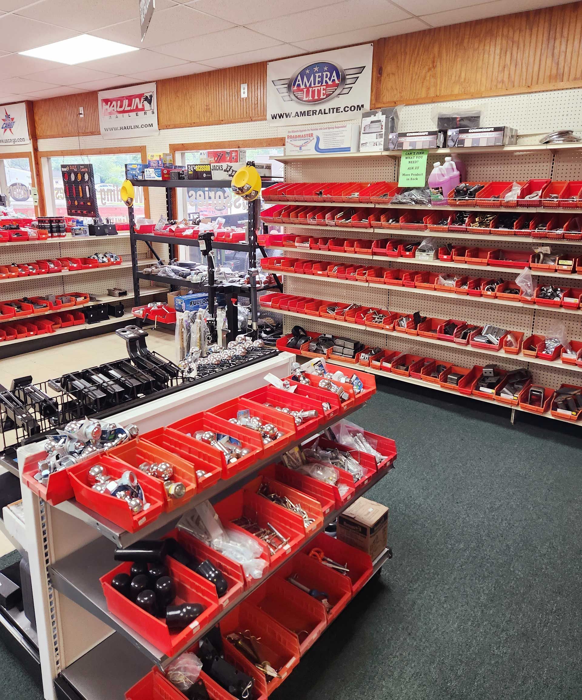 Tool store aisle with red bins of hardware parts and shelving along the walls