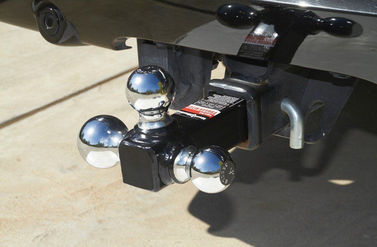 Chrome trailer hitch ball mount on a black vehicle, with three shiny balls attached.