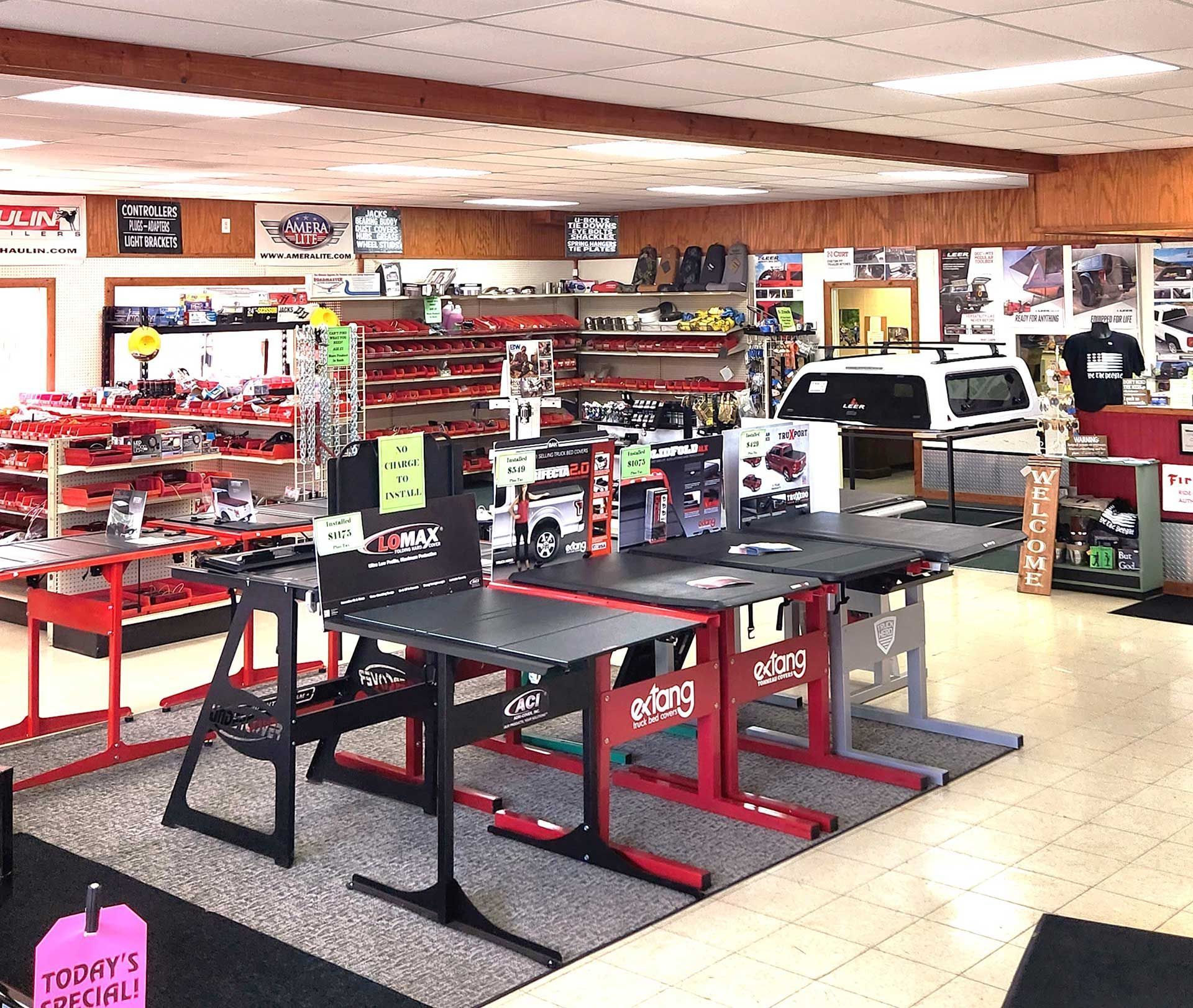 Auto parts store interior with red shelving, display tables, and a white pickup truck near the back