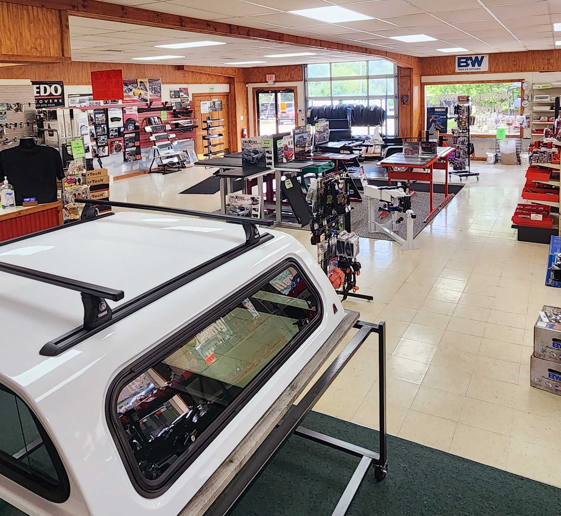 Indoor display of truck camper shells and accessories in a showroom with bright windows and tiled floor