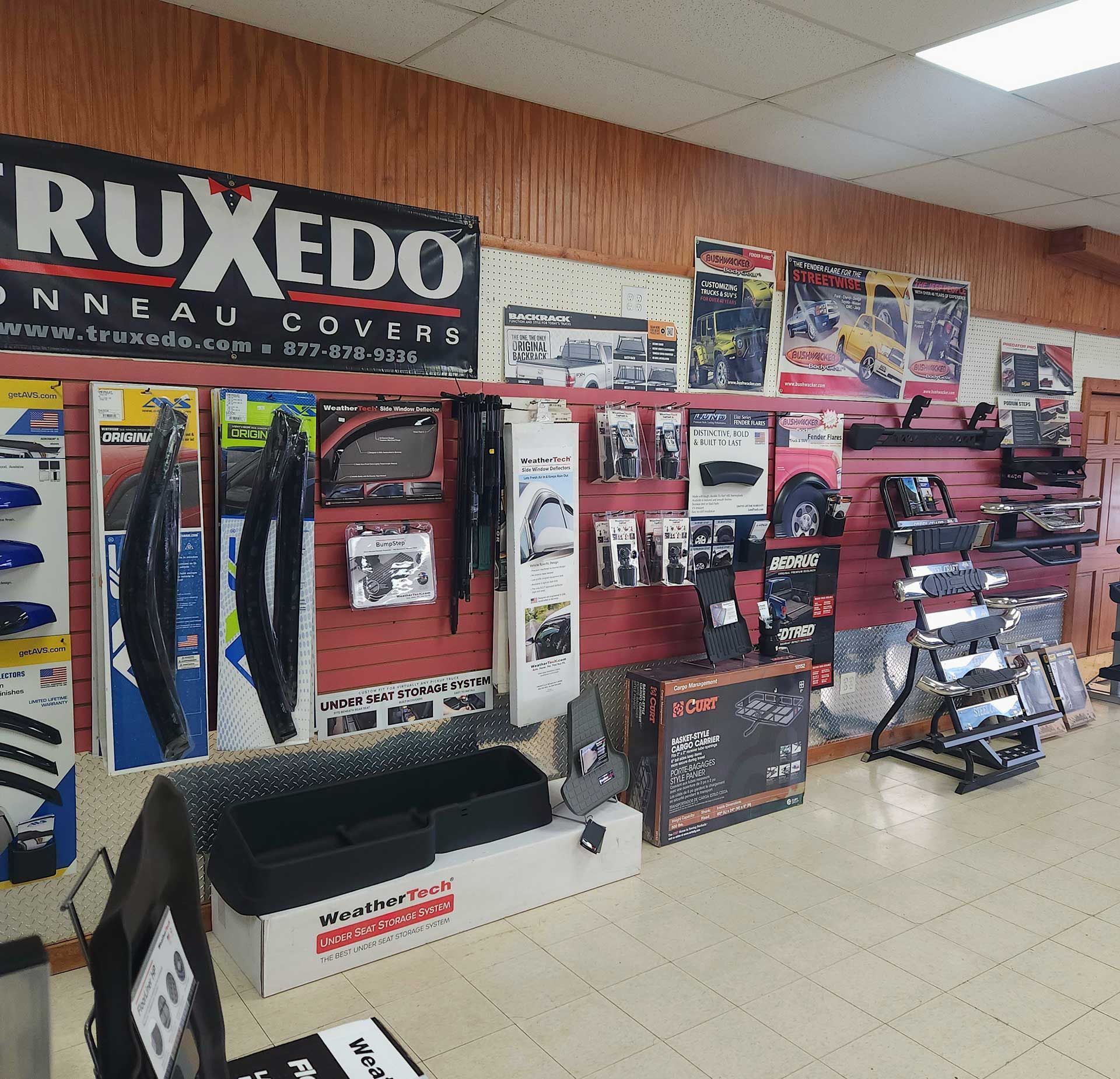 Automotive parts shop display with car accessories, banners, and a glass display case on a tiled floor.